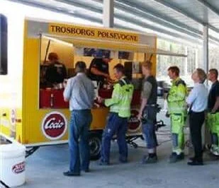 Gæster ved Trosborgs gule pølsevogn til et indendørs arrangement